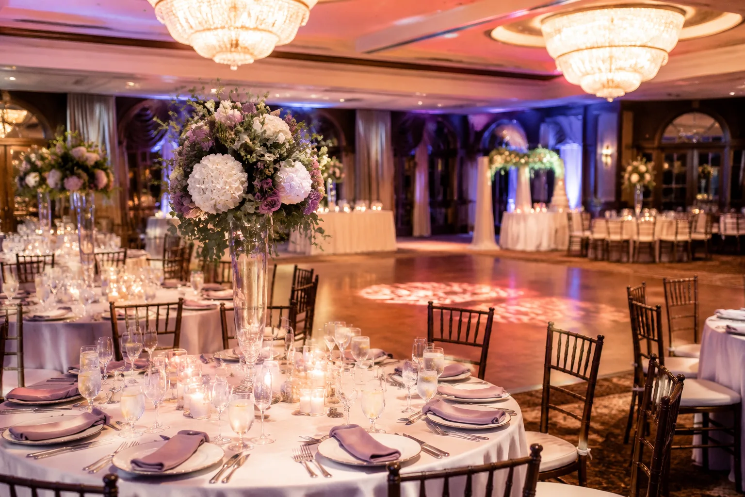 Climate-controlled indoor wedding reception hall with elegant chandelier lighting, round tables, and a dance floor