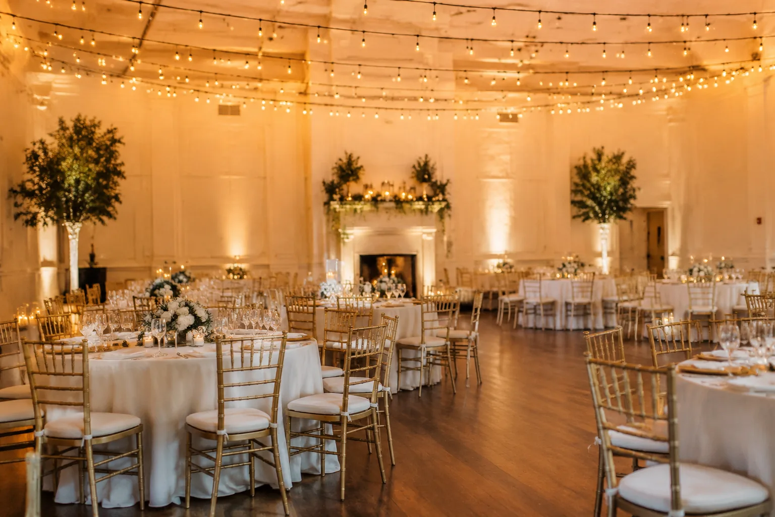 A photorealistic interior shot of an elegant indoor ballroom reception space set up for a wedding, round tables with white linens, string
